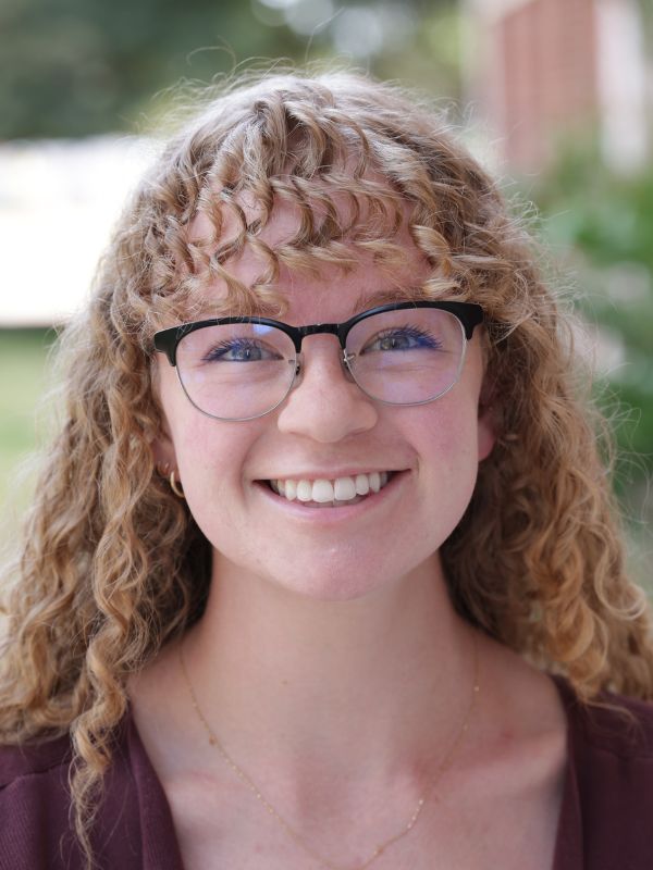 view of a smiling young woman with glasses and beautiful blonde curly hair