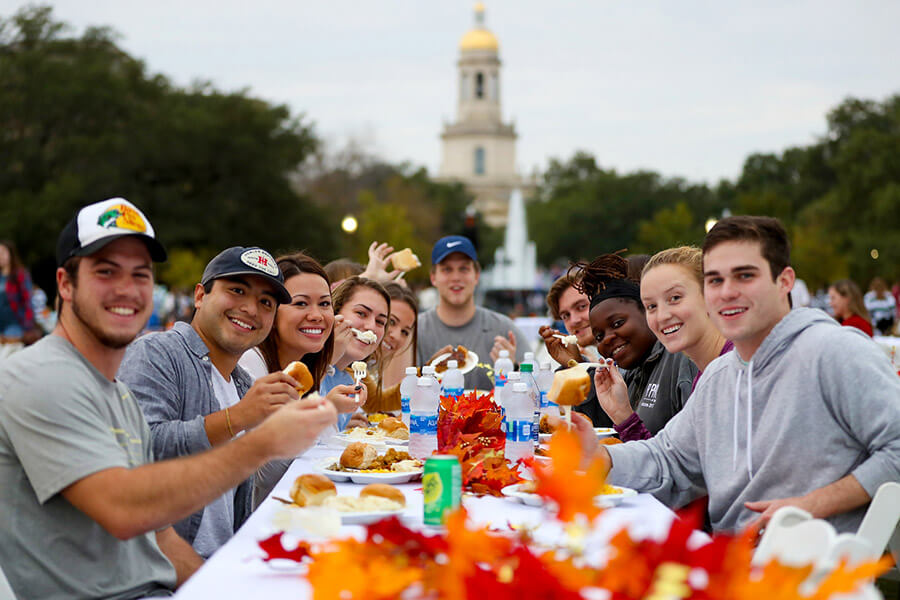 A group of students enjoying a Thanksgiving meal at a table outside