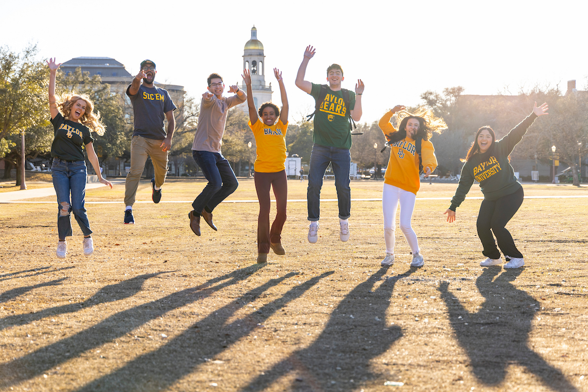 view of students smiling and jumping in front of Pat Neff Hall