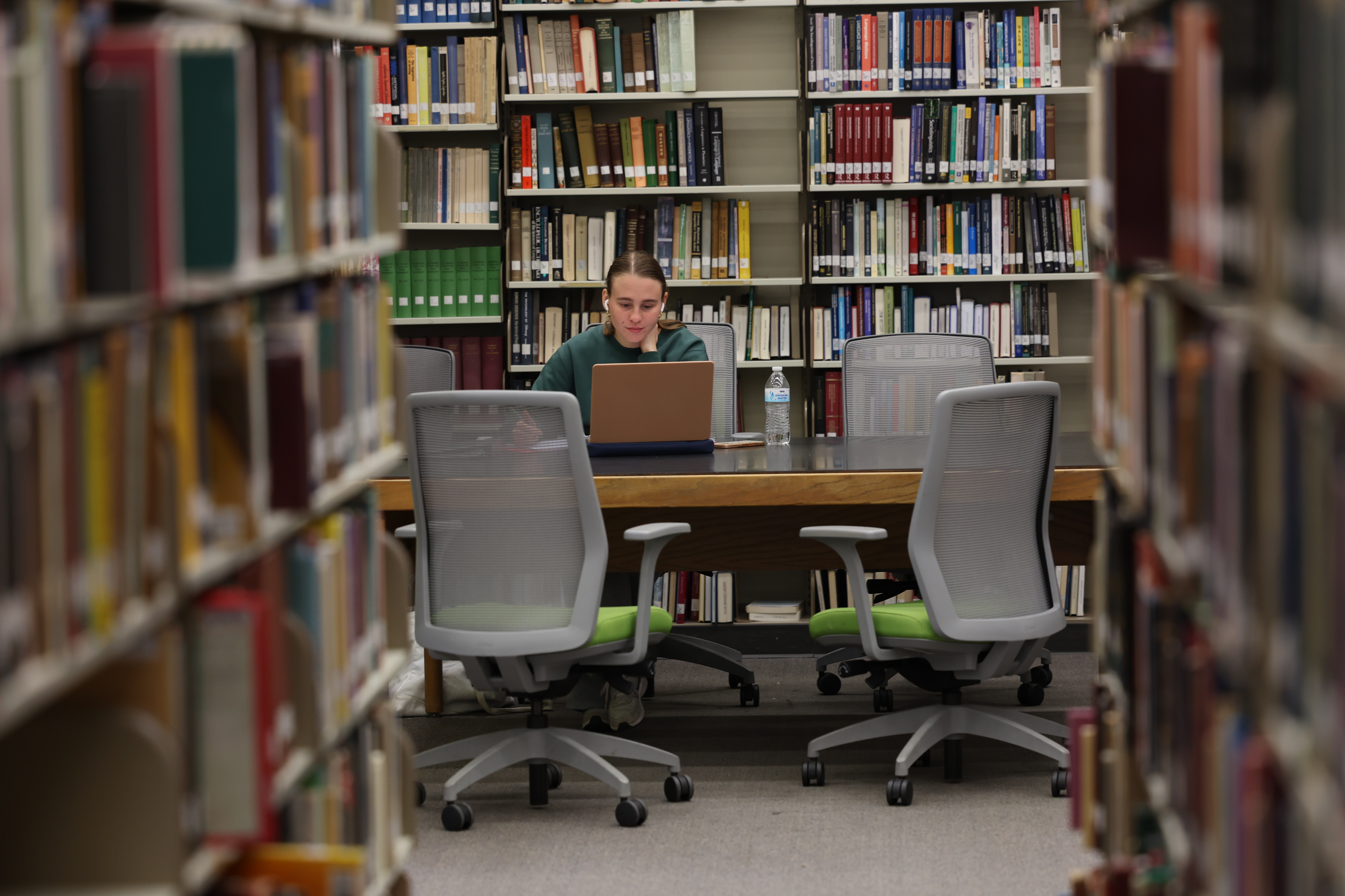 view of a postdoc student in the library surrounded by books, studying