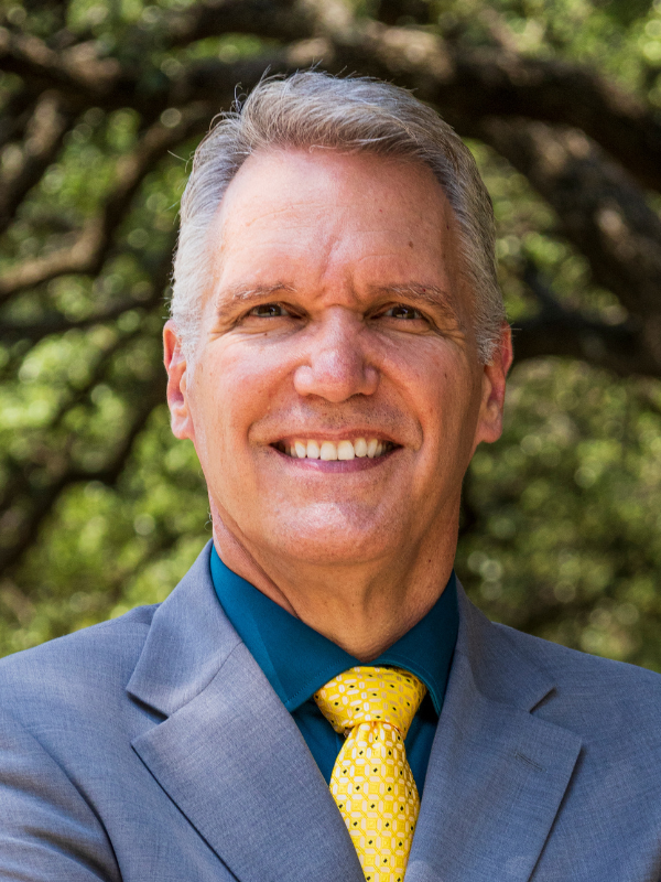 view of a smiling Midwesterner wearing a blue suit and gold spotted tie